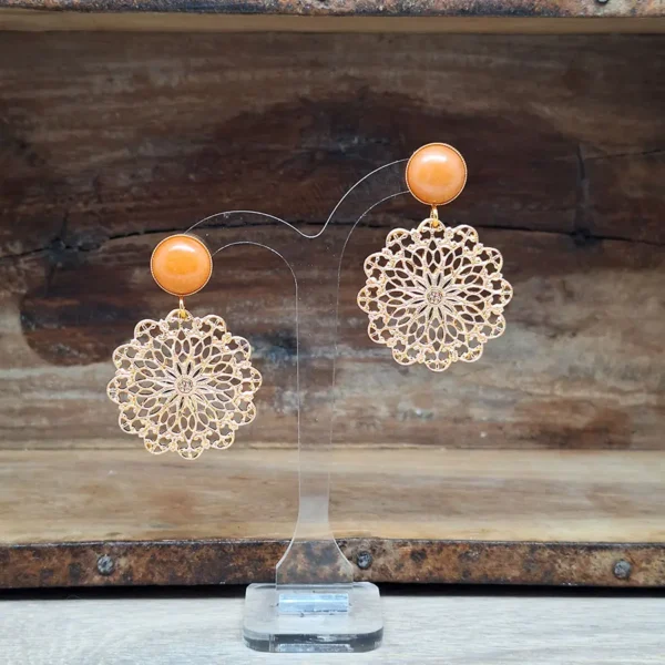 Vergoldete Ohrringe mit Ornamenten. Runde florale Ornamente hängen an vergoldeten Ohrsteckern mit orangenem Aventurin