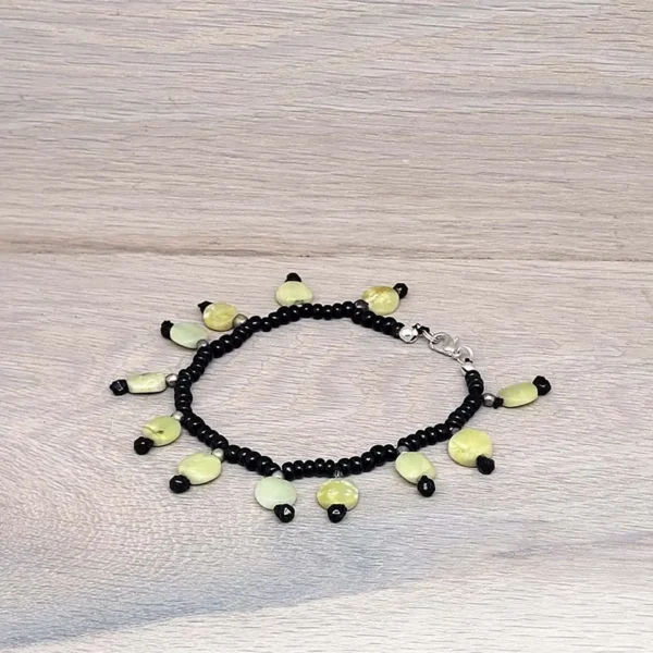 Perlenarmband aus Onyx Perlen mit kleinen Plättchen aus gelber Jade, die wie Charmes an das Armband angebracht sind